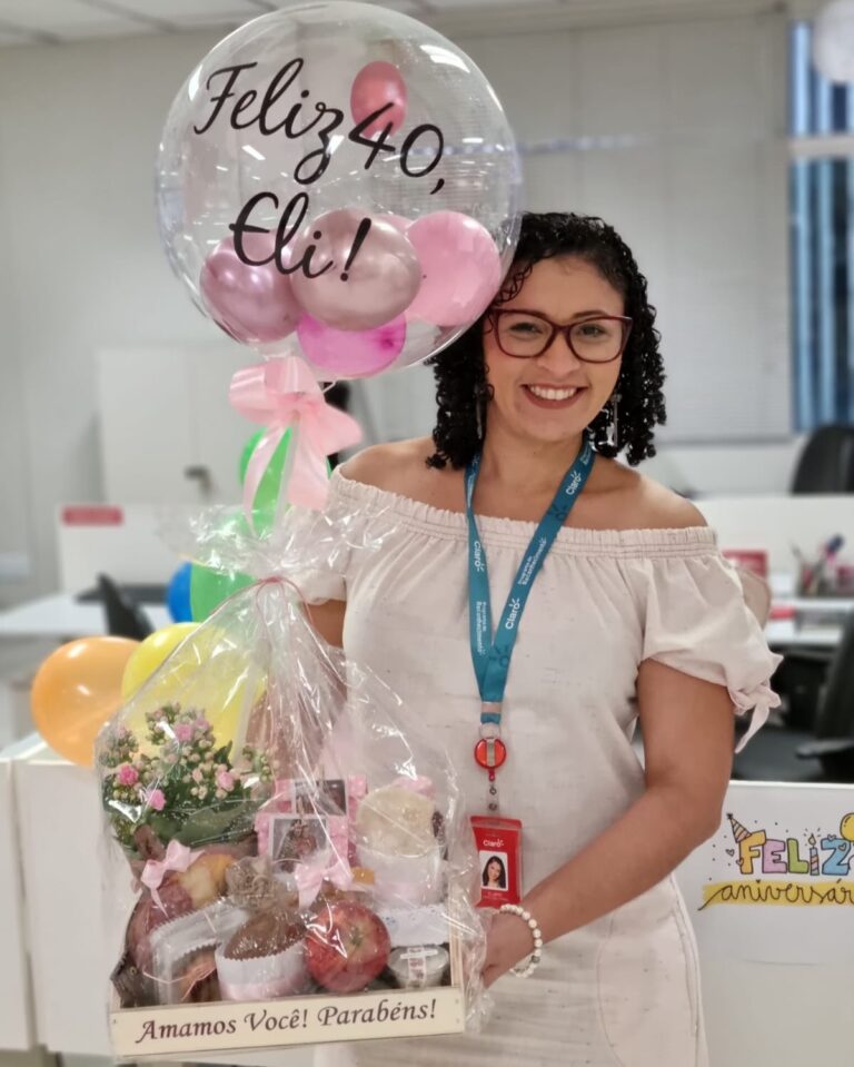 Cliente do sexo feminino , feliz por receber uma linda Cesta de café da manhã, com balão personalizada, parabenizando pelos 40 anos de idade, no seu trabalho.