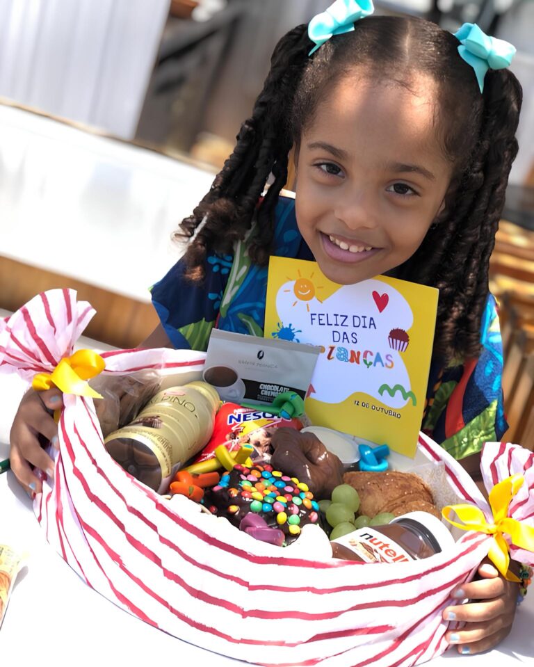 Menininha, feliz por receber uma linda Cesta infantil de guloseimas. Sorriso radiante para foto.
